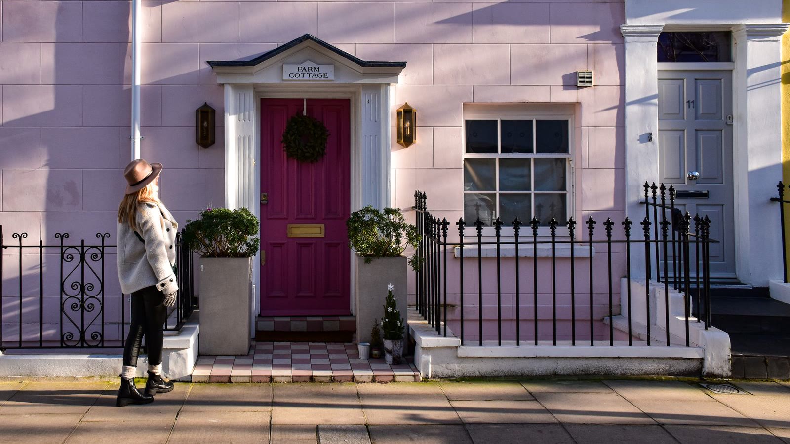A woman arriving outside a London terrace with a magenta front door