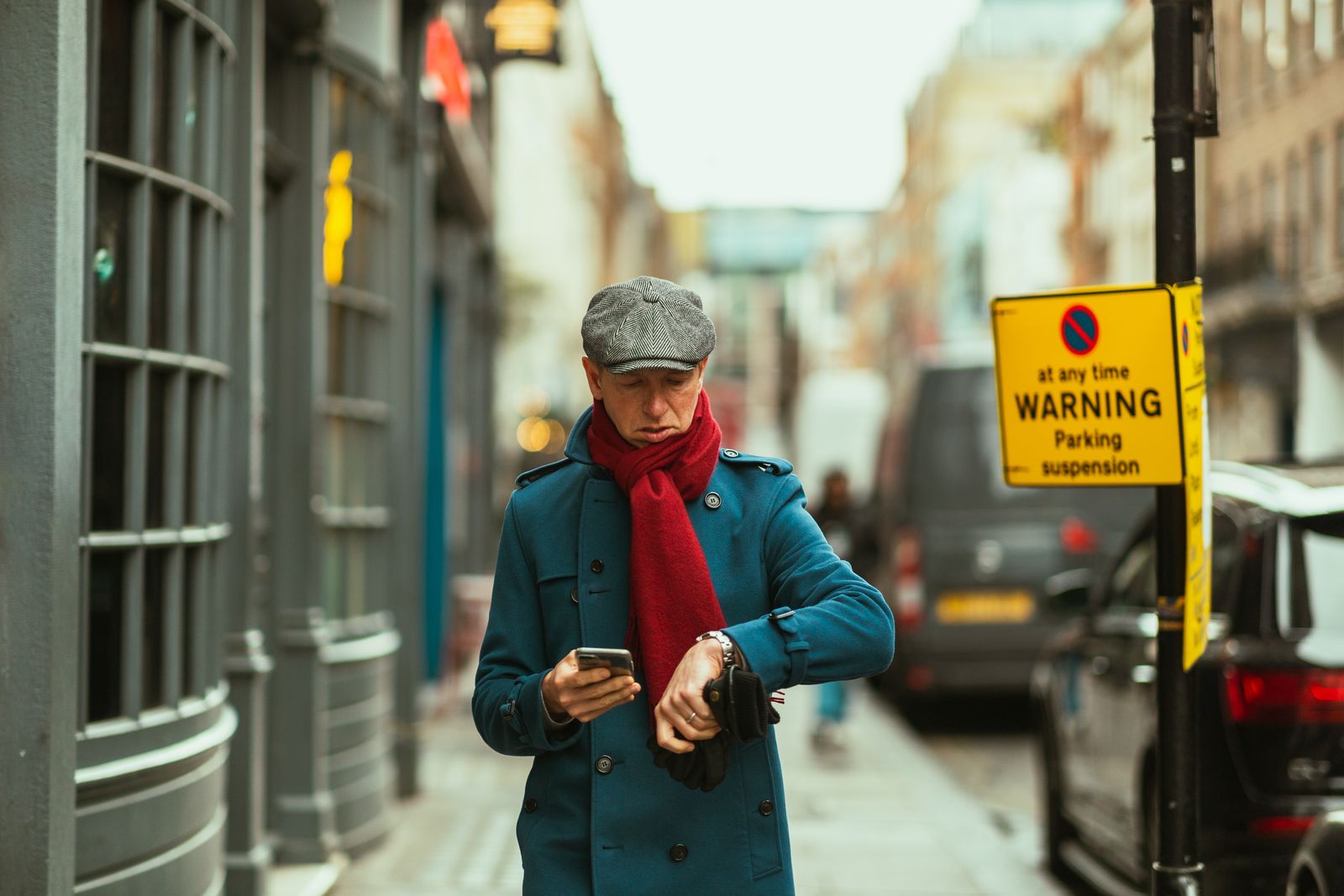 A negotiator in a flat cap checking his watch on a UK street