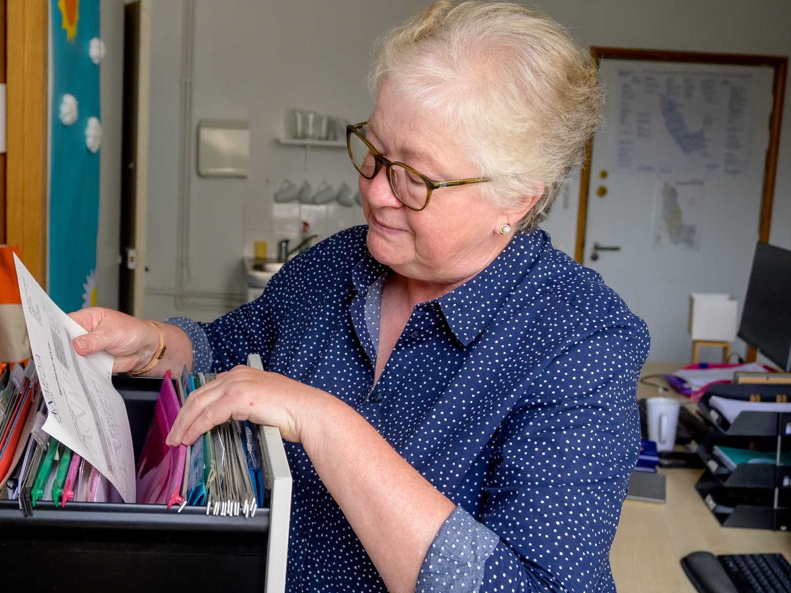 An office worker lifting a letter out of a hanging file drawer