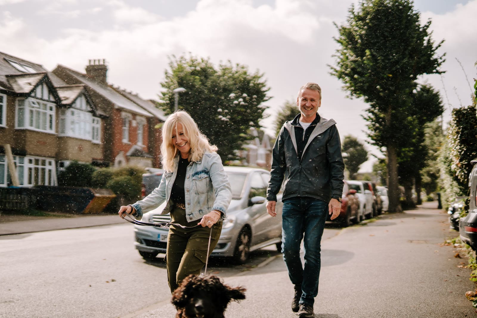 A couple walking their dog along a quiet residential street
