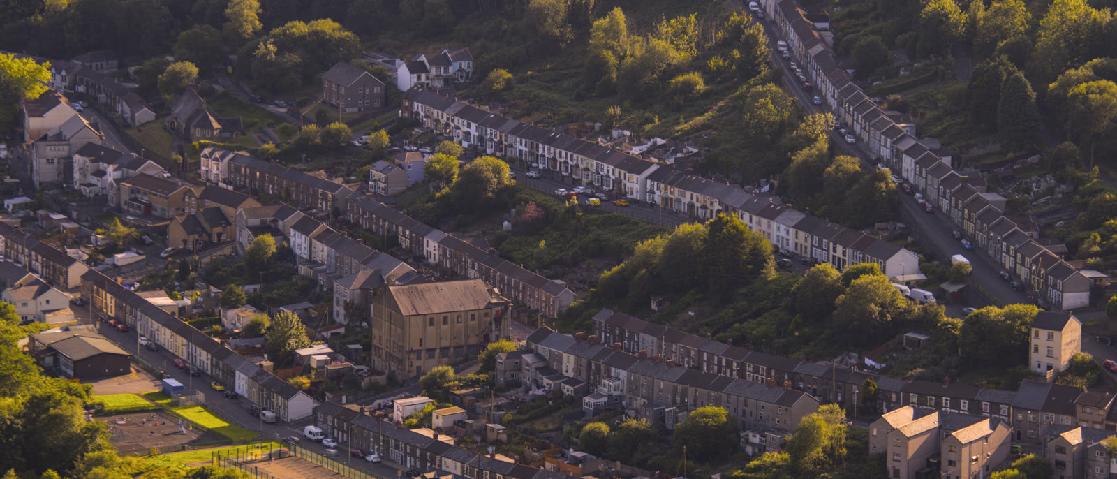 Rows of terraced houses across a valley town at golden hour