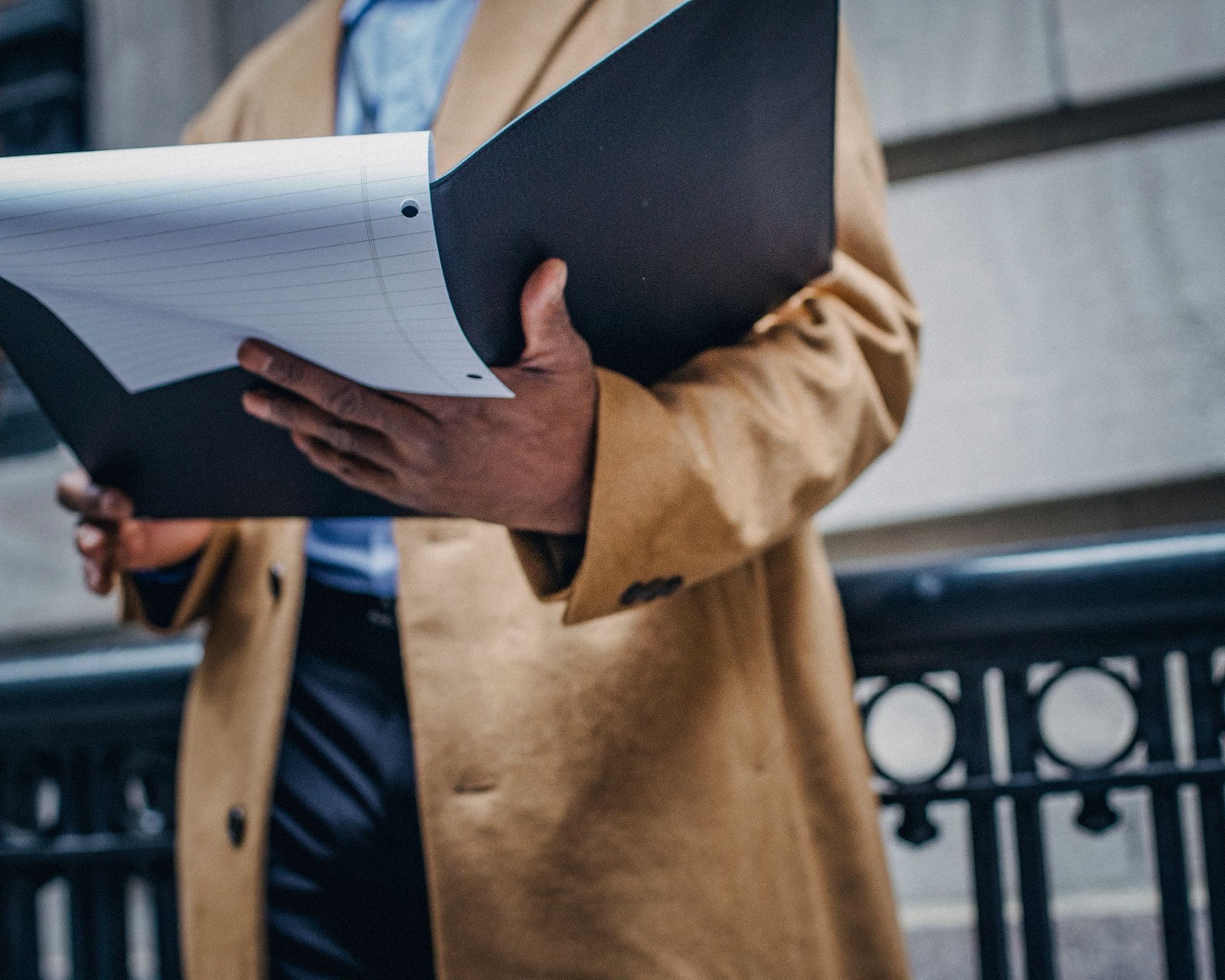 Holding a folder of printed property particulars in the street