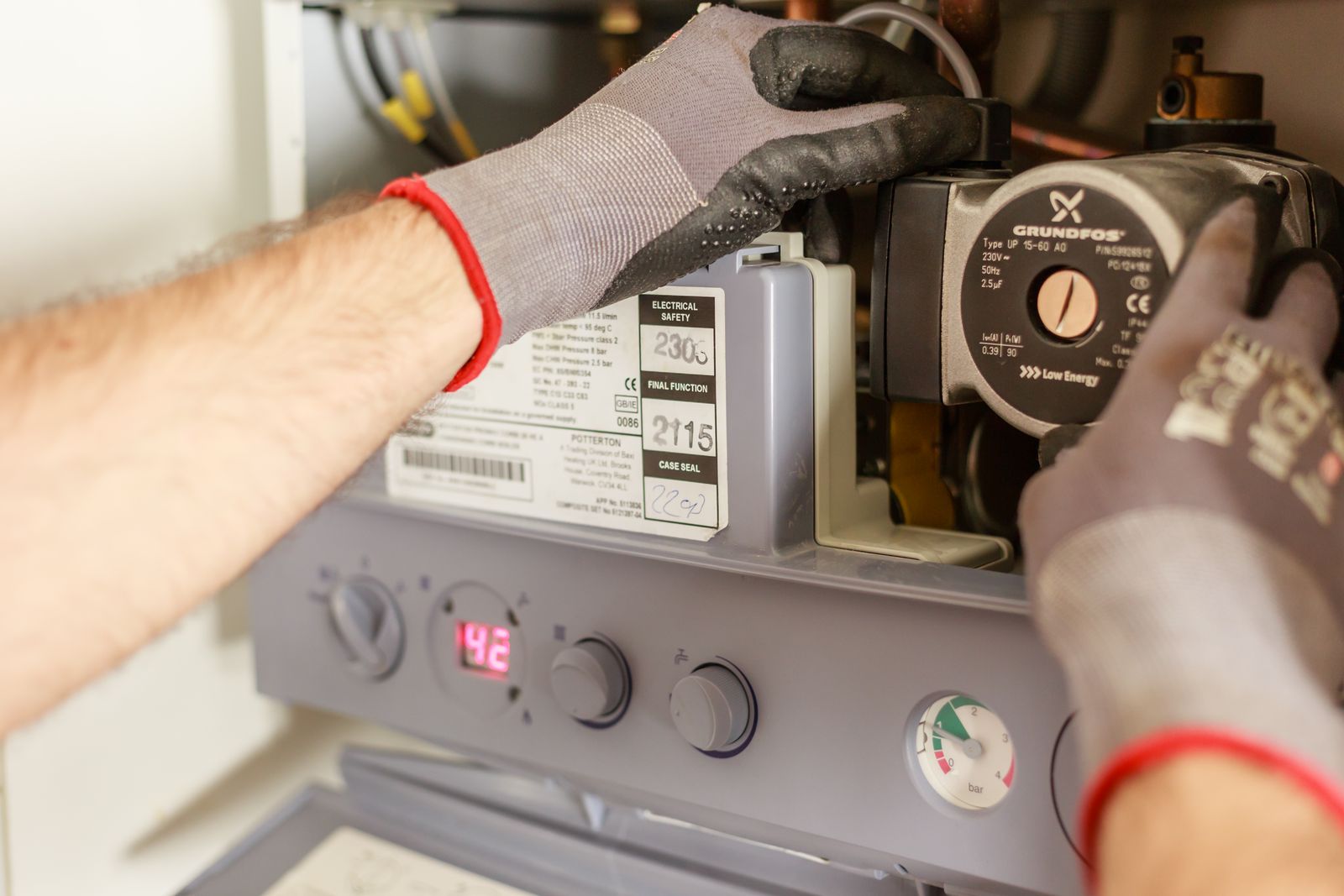 Gloved hands working on a domestic boiler