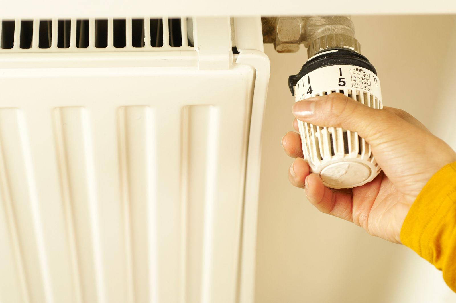 A hand turning a radiator valve