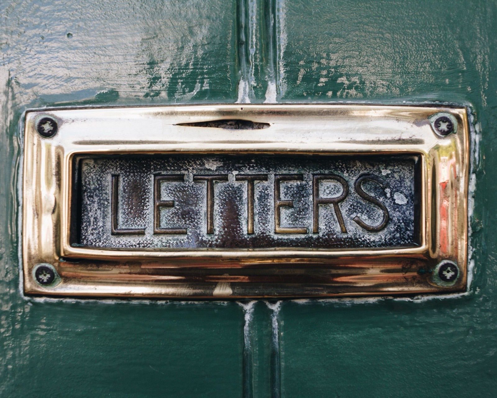 A brass letterplate on a painted front door