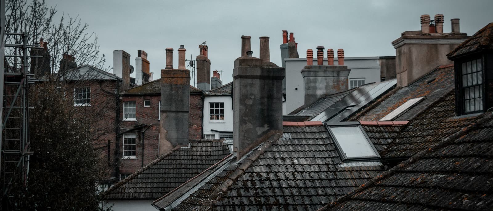 Rooftops and chimney pots on a UK street under a grey sky